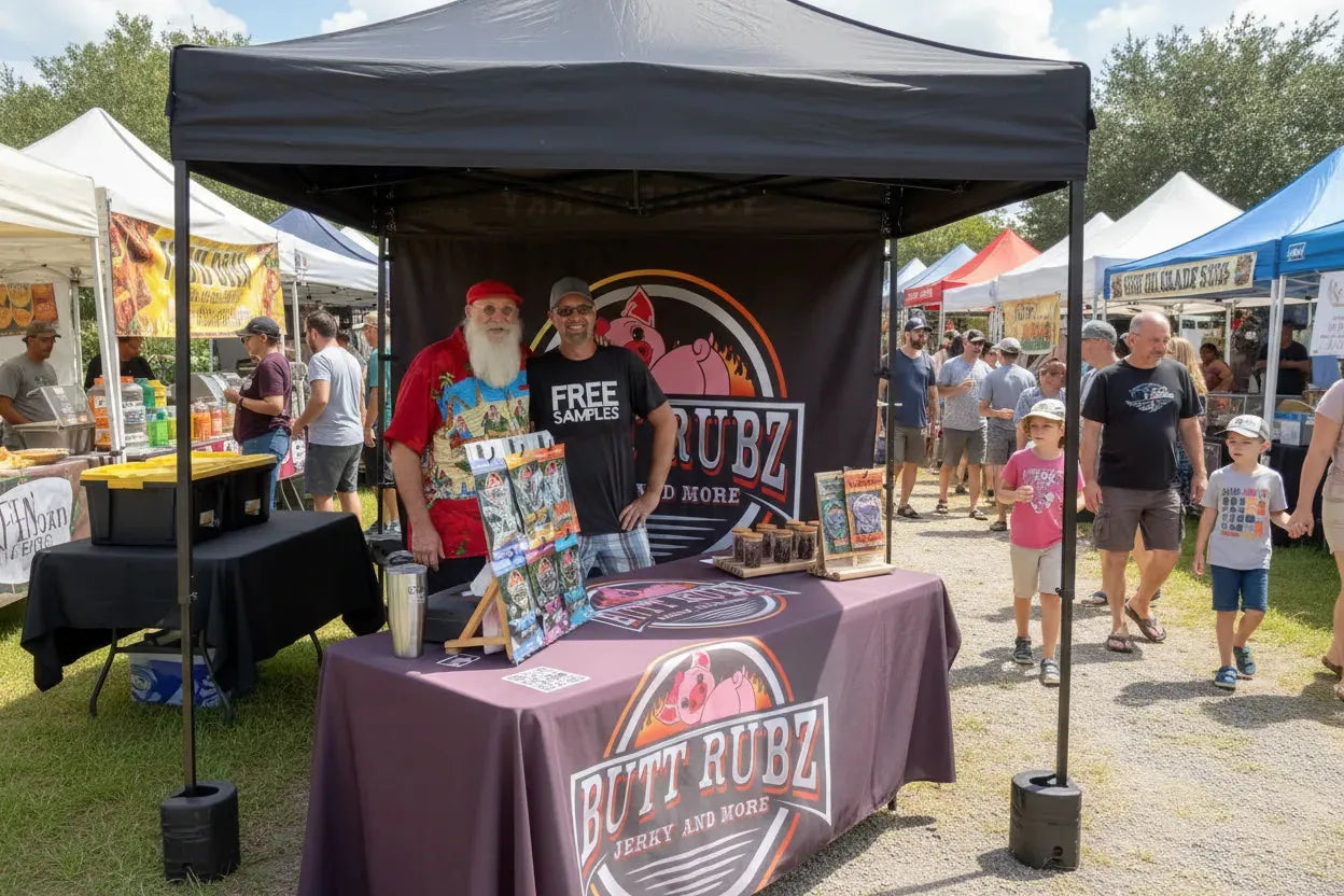 Custom branded pop-up tent and table setup for Butt Rubz Beef Jerky at an outdoor vendor market