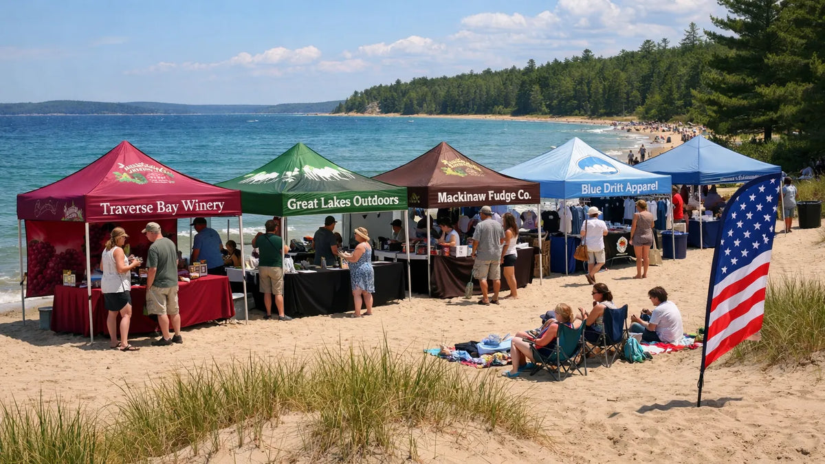 Custom branded pop-up canopy tents set up at a beachside vendor event in Northern Michigan with businesses, families, and feather flags along the Lake Michigan shoreline